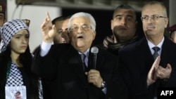 Palestinian President Mahmoud Abbas, center, delivers a speech as Palestinian Prime Minister Rami Hamdullah, right, claps during a ceremony to celebrate the 50th anniversary of the start of the Fatah movement, in the West Bank city of Ramallah, Dec. 31, 2014.