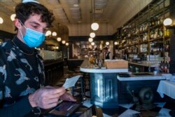 Restaurant host Joey Tyler verifies a patron's vaccination card at French restaurant Petit Trois in Los Angeles, California, Nov. 5, 2021.
