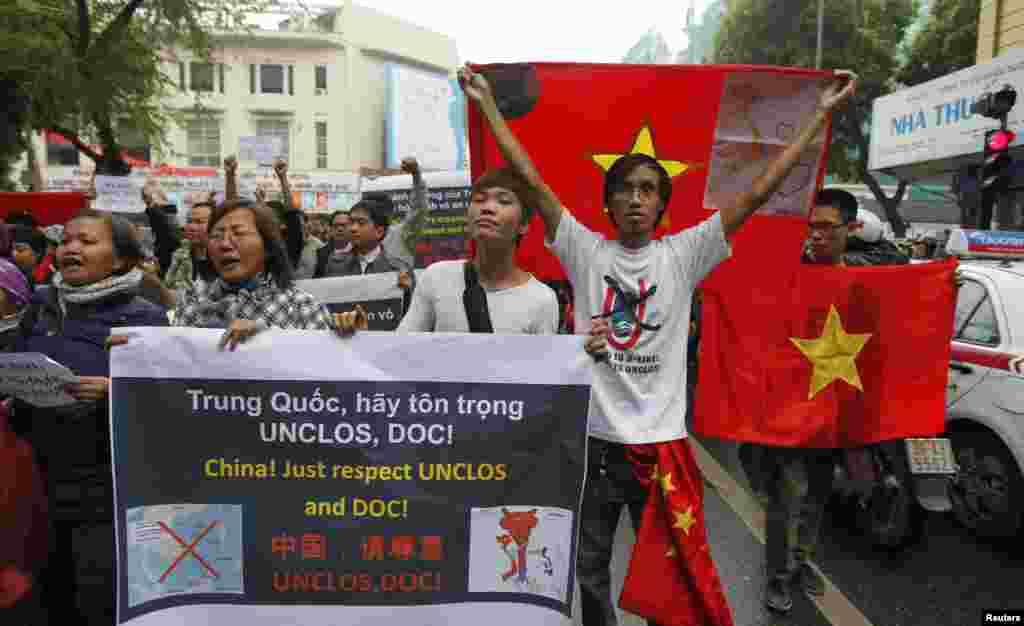 Anti-China protesters hold Vietnamese national flags and anti-China banners while marching on a street in Hanoi, December 9, 2012. 