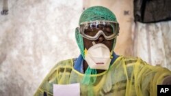 FILE - A health worker examines patients for Ebola inside a screening tent, at the Kenema Government Hospital in Sierra Leone. 
