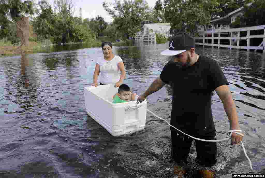 یکی از اهالی ایالت فلوریدا پس از توفان دریایی ایرما برای حمل فرزندش از یک یخدان شناور روی آب استفاده می کند.