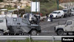 Israeli security forces inspect the scene of what the Israeli military said were back-to-back gun and car-ramming attacks by Palestinians, near the Jewish settlement of Kiryat Arba near the West Bank city of Hebron, March 14, 2016.