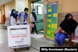 Seorang petugas menarik sebuah kotak berisi vaksin virus corona (COVID-19) di sebuah puskesmas untuk program vaksinasi massal, di Jakarta, 13 Januari 2021. (Foto: Willy Kurniawan/Reuters)