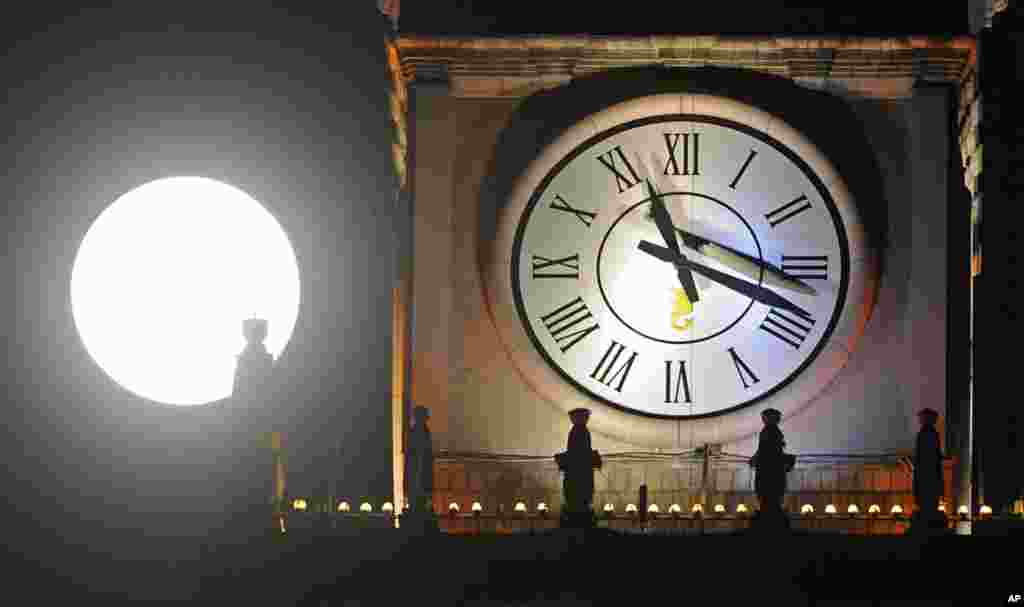 A supermoon rises next to a clock on top of the Palace of Culture in Warsaw, Poland, Sunday, Aug. 10, 2014.