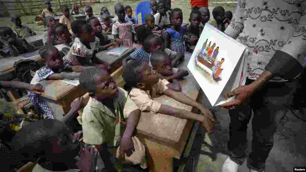 A man shows a picture to students during a United Nations Children's Fund (UNICEF) Ebola awareness drive in Gueupleu, Man, western Ivory Coast, Nov. 3, 2014. 