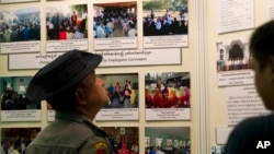 A Myanmar police officer looks at photos displayed during a press conference of Maungdaw Investigation Commission at a government guest house Sunday, Aug.6, 2017, in Yangon, Myanmar. The Myanmar government's inquiry into violence in northern Rakhine state last year that forced tens of thousands of Muslim Rohingya to flee to Bangladesh and led to U.N. accusations of crimes against humanity by the army has concluded that no such crimes happened.