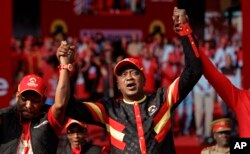 Kenya's President Uhuru Kenyatta, center, joins hands with Nairobi Senator Mike Sonko, left, at an election rally in Uhuru Park in downtown Nairobi, Aug. 4, 2017.