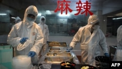 Cooks wearing hazardous material suits prepare lunch for workers at a garment factory, the Zhejiang Ugly Duck Industry in Wenzhou on February 28, 2020. (Photo by NOEL CELIS / AFP)