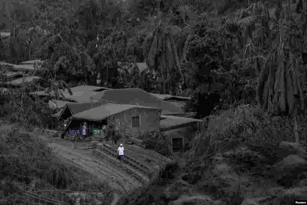 A man walks on a road covered with ashes from the Taal Volcano in Talisay, Batangas, Philippines.