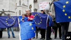 EU membership supporters hold EU flags on the first day of hearings in a lawsuit on whether Prime Minister Theresa May’s government can trigger Britain's exit from the EU without an act of parliament, at the High Court, in London, Oct. 13, 2016.
