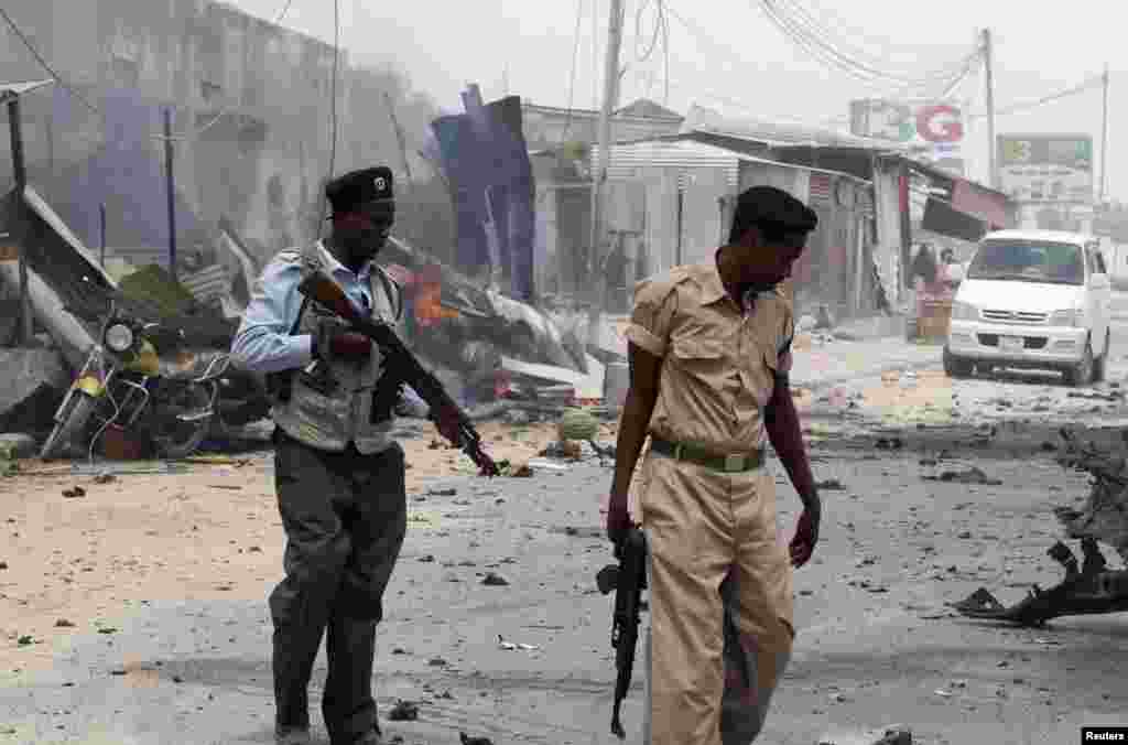 Polisi wa Somalia wakikakua eneo la mlipuko wa bomu karibu na mlango wa uwanja wa ndege wa Mogadishu, Feb. 13, 2014.
