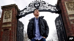 Harvard University graduate Jin K. Park, who holds a degree in molecular and cellular biology, poses at a gate at Harvard Yard in Cambridge, Mass., Thursday, Dec. 13, 2018. (AP Photo/Charles Krupa)
