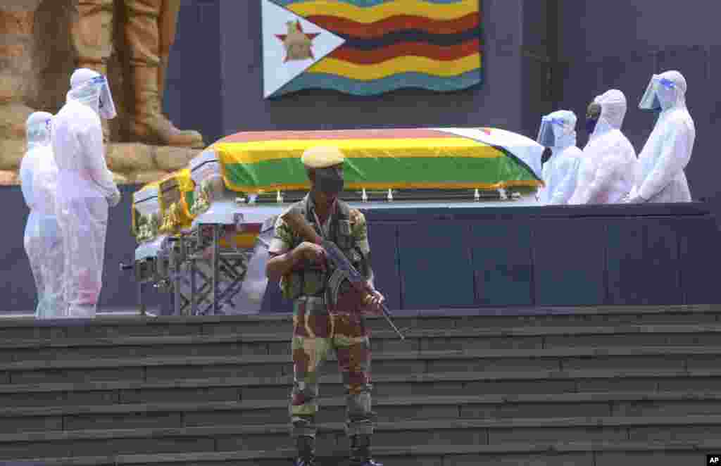 Pallbearers stand next to the coffins of three top government officials who succumbed to COVID-19, prior to their burial, at the National Heroes Acre in Harare, Zimbabwe.