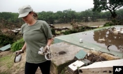Amanda Calaway pulls unbroken cups and bowls from the debris where a cabin was stripped from its foundation behind her in flood waters from the Blanco River days earlier, May 26, 2015, in Wimberley, Texas.