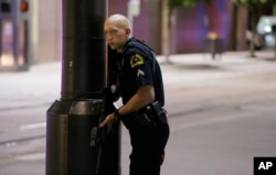 FILE - A Dallas policeman keeps watch on a street in downtown Dallas, Thursday, July 7, 2016.