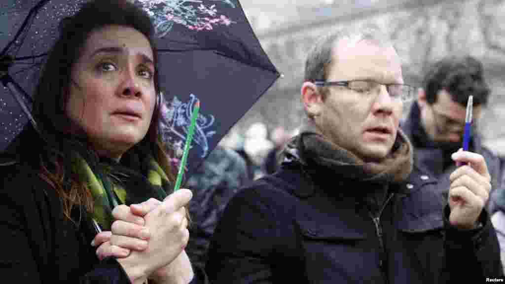 Une femme tenant un crayon pleure lors d&#39;un rassemblement&nbsp;en face de la cathédrale Notre-Dame pendant la minute de silence pour les victimes de la fusillade mercredi dans les bureaux Charlie Hebdo, à Paris, le 8 janvier 2015.ris, Jan. 8, 2015.