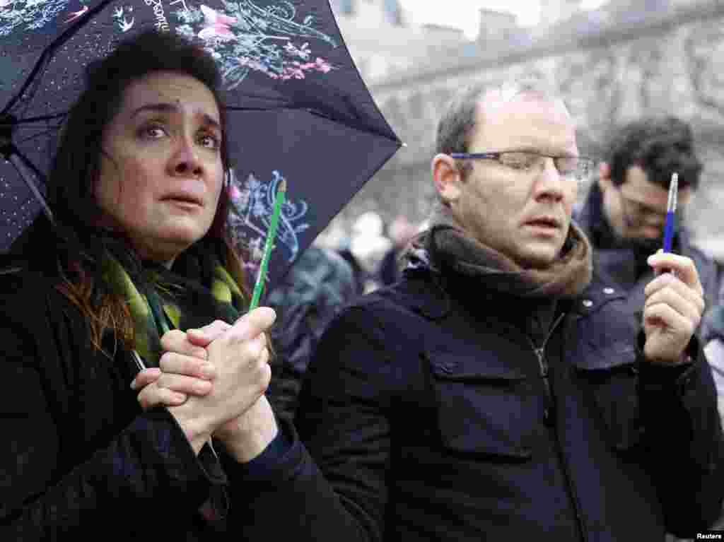 A woman holding a pencil cries as she gathers in front of the Notre Dame Cathedral during a minute of silence for victims of the shooting Wednesday at the Charlie Hebdo offices, in Paris, Jan. 8, 2015.
