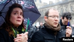 星期四巴黎人手举铅笔和钢笔站在严寒的雨中悼念《查理周刊》屠杀案的遇难者