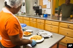 Jon Morales, left, chef at the Haven apartments, prepares dinner featuring bake talapia for residents at three dollars a plate, Dec. 8, 2015, Bronx, N.Y.