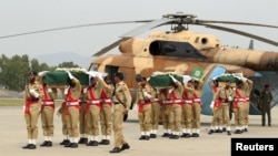 Pakistani army soldiers carry coffins, wrapped in national flags and carrying bodies of helicopter crash victims, at the Nur Khan air base in Islamabad, May 9, 2015. 