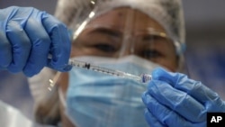 FILE - A health worker prepares to administer Russia's Sputnik V COVID-19 vaccine inside the Makati Coliseum, in Manila, Philippines on May 4, 2021. On Monday, the U.S. will implement a new air travel policy to allow in foreign citizens who have completed