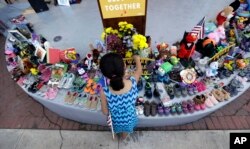 Una niña coloca un objeto junto a una colección de zapatos y juguetes antes del evento "Rally for Our Children", en San Antonio, Texas, para protestar contra una nueva política de inmigración de "cero tolerancia" que ha llevado a la separación de familias. 31 de mayo de 2018.