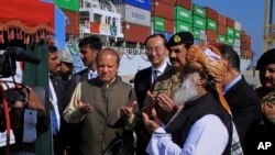Perdana Menteri Pakistan Nawaz Sharif (tengah) dan Komandan Angkatan Darat Jenderal Raheel Sharif (keempat dari kanan), berdoa setelah meresmikan rute baru perdagangan internasional di pelabuhan Gwadar, 700 kilometer dari Karachi (13/11). (AP/Muhammad Yousuf)