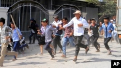 Cambodian garment workers run as they escape for safety in front of a factory of Yak Jin in Kambol village on the outskirts of Phnom Penh, Cambodia, Thursday, Jan. 2, 2014. Troops have been used to forcefully quell a demonstration by striking factory workers in Cambodia, with Buddhist monks and labor leaders among those detained. (AP Photo/Heng Sinith)