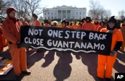 Protesters wearing orange jumpsuits depicting Guantanamo Bay detainees, hold a sign that reads "Not One Step Back Close Guantanamo" participate in a rally outside of the White House in Washington Monday, Jan. 11, 2016, calling for a close of the detention center at the U.S. base at Guantanamo Bay, Cuba.