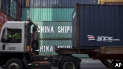 FILE - A truck passes a stack of 40-foot China Shipping containers at the port of Savannah in Savannah, Ga., July, 5, 2018.