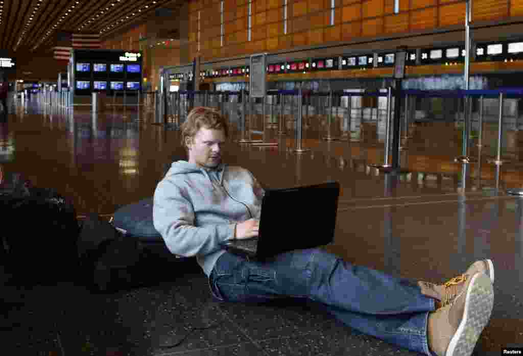 Rasmus Thomsen of Denmark works on his computer as he waits at Boston Logan International Airport after flights were cancelled or delayed due to a massive winter storm, in Boston, Massachusetts Feb. 8, 2013. 