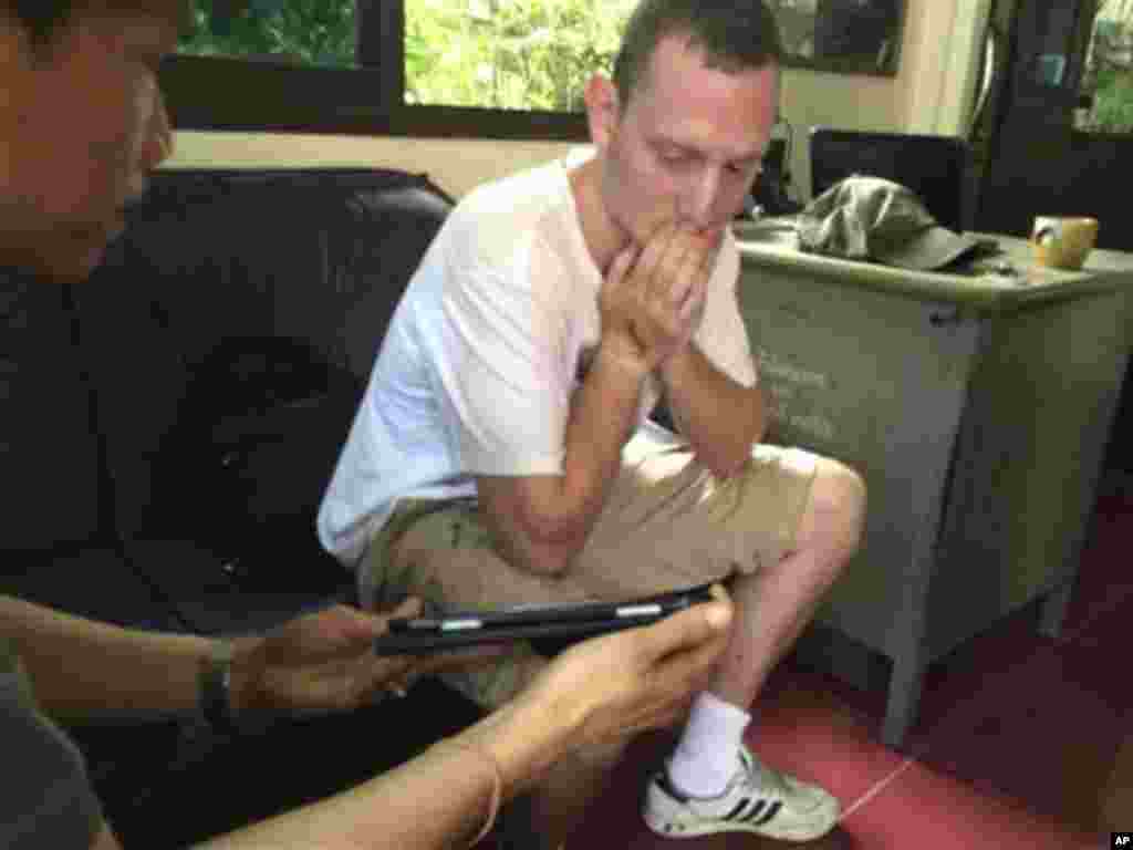 In this photo taken Tuesday, Sept. 16, 2014 and released by Royal Thai police, Christopher Ware, a British friend of British tourist David Miller who was killed along with his girlfriend, reacts during an investigation at a police station in the resort island of Koh Tao in the Gulf of Thailand. Police said Wednesday, Sept. 17, they have conducted autopsies on the two British tourists whose bludgeoned bodies were found on the island this week. (AP Photo/Royal Thai Police)