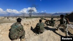 FILE - Afghan security forces take position during a gun battle between Taliban and Afghan security forces in Laghman province, Afghanistan, March 1, 2017. 