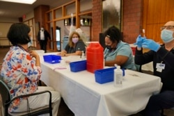 Cristina Licup, left, waits to receive her COVID-19 booster shot where she works at the Hebrew Home at Riverdale in New York, Monday, Sept. 27, 2021. (AP Photo/Seth Wenig)