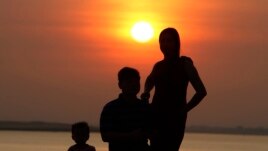 A family takes a photo as the sun rises in Phnom Penh, Cambodia, Friday, Jan. 24, 2020. ((AP Photo/Heng Sinith))
