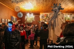 People in Fasnacht masks walk in a circle to "scare away old man winter," hanging in the center.