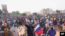 FILE - FILE - Nigeriens, some holding Russian flags, participate in a march called by supporters of coup leader Gen. Abdourahmane Tchiani in Niamey, Niger, on July 30, 2023.