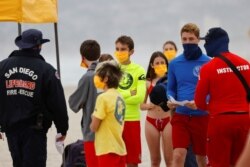 Instructors gather participants on the beach as San Diego's Junior Lifeguard Program officially reopens with new protocols in place to comply with county health guidelines for novel coronavirus safety.