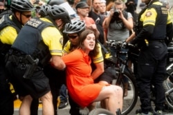 Police officers detain a protester against right-wing demonstrators following an "End Domestic Terrorism" rally in Portland, Ore., on Saturday, Aug. 17, 2019.