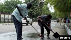 Des civils du Soudan du sud nettoient les rues du sang séché d'un soldat tué devant la maison d'Etat présidentielle dans la capitale, Juba, le 14 juillet 2016.