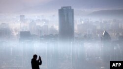 A person takes a picture of the smog over Santiago,