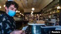 Restaurant host Joey Tyler verifies a patron's vaccination card at French restaurant Petit Trois in Los Angeles, California, Nov. 5, 2021.