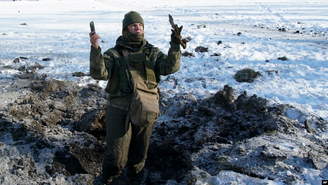 FILE - A Ukrainian soldier shows pieces of shrapnel in a crater left by an explosion in Avdiivka, Ukraine, Jan. 31, 2017.