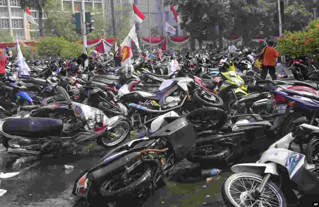 Sejumlah sepeda motor yang digeletakkan begitu saja oleh para pendukung kandidat presiden yang kalah, Prabowo Subianto, yang dibubarkan oleh polisi anti-huru-hara, terlihat di jalan menyusul bentrokan dekat Mahkamah Konstitusi di Jakarta (21/8). (AP/Tatan Syuflana)