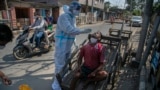 A health worker takes a nasal swab sample of a cartpuller during random testing for COVID-19 in a market in Gauhati, India.