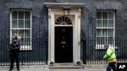 FILE - A street cleaner clears fall leaves from the front of 10 Downing Street, London, Britain, Nov. 6, 2019. 