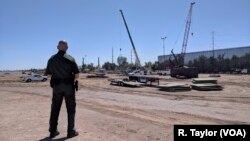 Border Patrol Sector Supervisor Jorge Rivera watches as construction workers build a portion of 9-meter-tall replacement fencing in Calexico, Calif. 