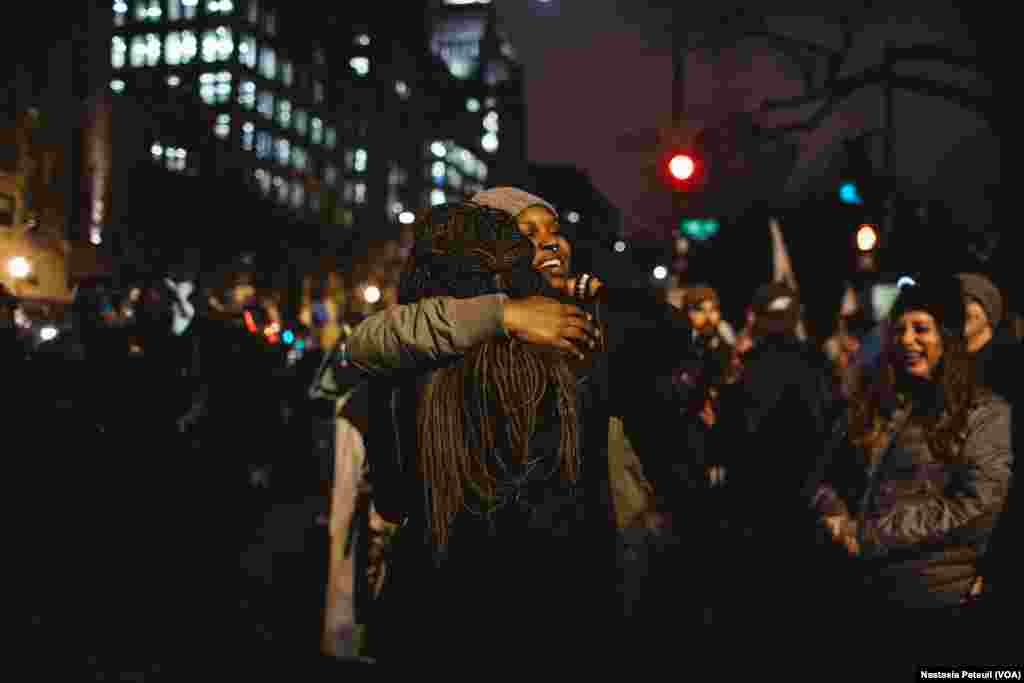 Sur la place Franklin, deux jeunes filles se tiennent dans les bras devant la police, à Washington DC, le 20 janvier 2017. (VOA/Nastasia Peteuil)