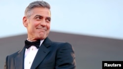 U.S. actor George Clooney smiles as he arrives on the red carpet for the premiere of "Gravity" at the 70th Venice Film Festival in Venice, August 28, 2013. 