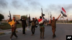 Iraqi security forces and allied Shi'ite militiamen celebrate in central Tikrit, 80 miles (130 kilometers) north of Baghdad, March 31, 2015.